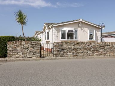 A single story house with a stone wall and metal gate in front at Summer Breeze Tregolds near St Merryn
