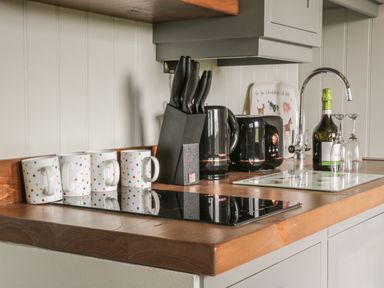 A kitchen countertop with four polka dot mugs a black knife block kettle and toaster a bottle of wine and two wine glasses at Ewes Welcome Cottingham