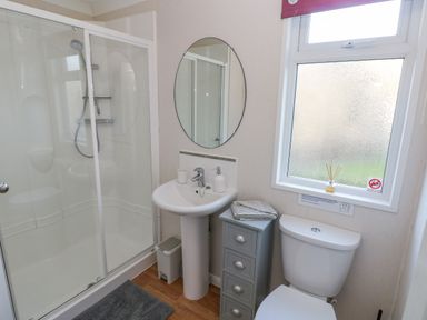 A bathroom with a shower enclosure sink with mirror small cabinet toilet and frosted window at The Hideaway - Heritage Park in Stepaside near Kilgetty