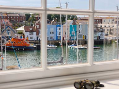 View through window of a harbor with boats and colorful buildings at Seasides in Weymouth