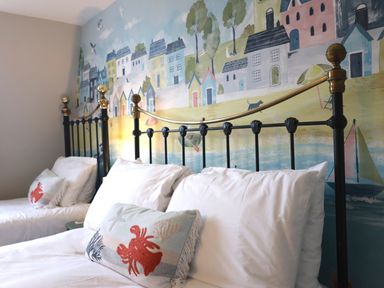 A bedroom with two beds and a mural at Seasides in Weymouth