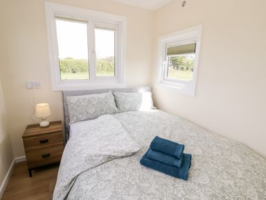 A bedroom with a bed covered in patterned bedding and blue towels on top at Malvern View Lodge in Wadborough near Pershore