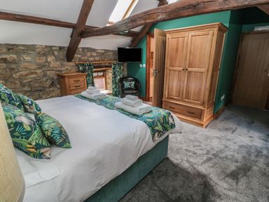 A bedroom with a bed folded towels wooden wardrobe and chest of drawers at Granary Cottage in Bellingham