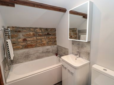 A bathroom with a bathtub sink mirror towel rack and toilet at Granary Cottage in Bellingham