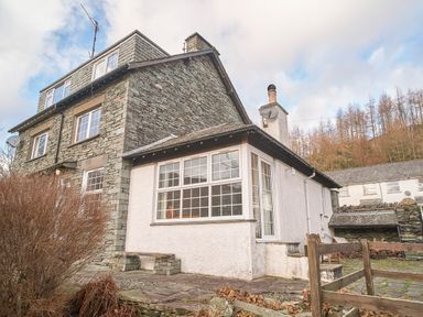 An exterior view of a stone and white plaster house with multiple windows and a chimney at Plumblands in Chapel Stile