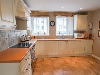A kitchen with white cabinets wooden countertops a stove microwave and sink at Plumblands in Chapel Stile