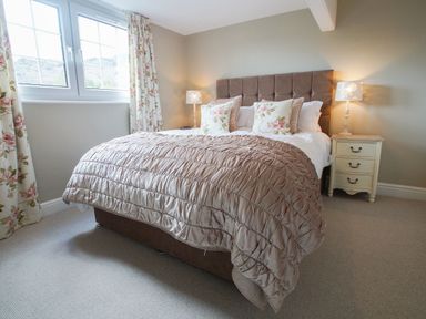 A bedroom with a bed covered by a quilt and pillows next to a window at Plumblands in Chapel Stile