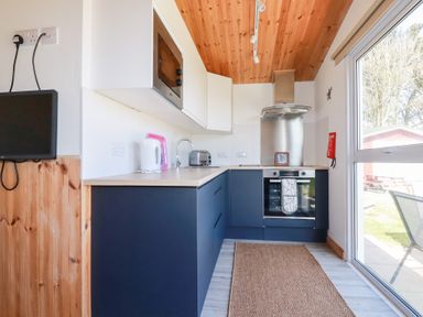 A kitchen with blue lower cabinets white upper cabinets a microwave toaster and kettle at 194 Atlantic Bays Atlantic Bays Holiday Park near St Merryn