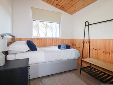 A bedroom with a single bed a bedside table with a lamp and an open clothes rack at 194 Atlantic Bays Atlantic Bays Holiday Park near St Merryn