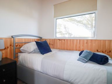 A bedroom with a single bed next to a window and a nightstand with a lamp at 194 Atlantic Bays Atlantic Bays Holiday Park near St Merryn
