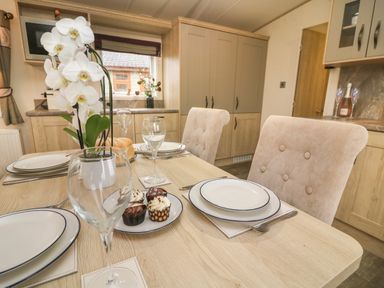 A dining table set with plates glassware and cupcakes in a kitchen at Lancaster Lodge in South Lakeland Leisure Village