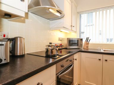 A kitchen countertop with a microwave toaster kettle pots stove and knife block near a window at Holme Rigg in Braithwaite