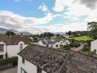 A village scene with white houses and hills in the background at Holme Rigg in Braithwaite
