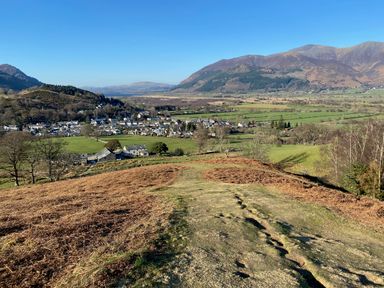 A rural landscape with hills fields scattered houses and mountains in the background at Holme Rigg in Braithwaite