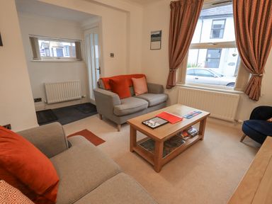 A living room with two sofas a wooden coffee table and patterned curtains at Holme Rigg in Braithwaite