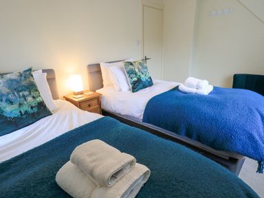 A bedroom with two single beds with blue blankets pillows and towels on the beds at Holme Rigg in Braithwaite