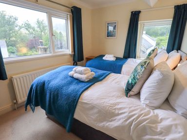 A bedroom with two beds each with blue blankets and white towels on top at Holme Rigg in Braithwaite