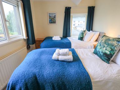A bedroom with two beds with blue blankets and white towels on top at Holme Rigg in Braithwaite