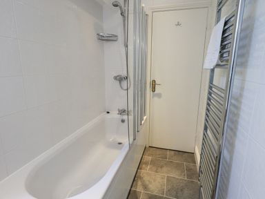 A bathroom with a bathtub shower combination and a towel radiator at Holme Rigg in Braithwaite
