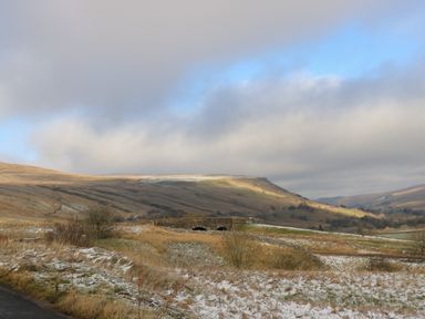 A landscape with hills a stone bridge and patches of snow at Fig Cottage in Kirkby Stephen