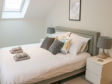 A bedroom with a bed with pillows and folded towels beside a window at Fig Cottage in Kirkby Stephen