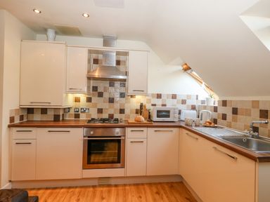 A kitchen with white cabinets brown countertop gas stove oven microwave toaster kettle and sink at Harbour Reach 6 in Weymouth