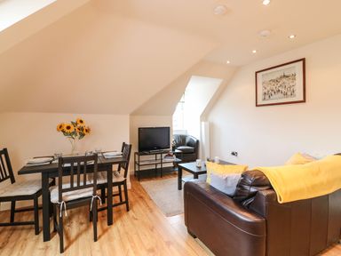 A living room with a dining table and chairs a sofa a coffee table a television and an armchair at Harbour Reach 6 Weymouth