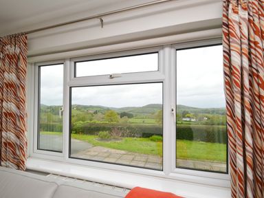 A window with patterned curtains overlooking a green landscape at Berwyn View in Trelydan near Welshpool