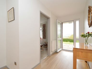 A hallway with wooden flooring an open door leading outside a wooden table with flowers and a mirror on the wall at Berwyn View in Trelydan near Welshpool