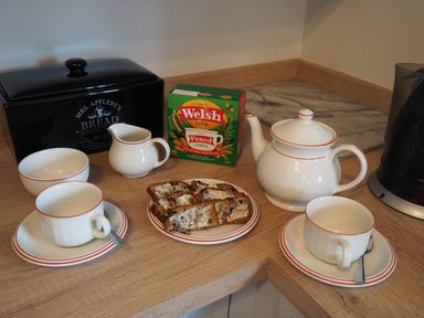 A kitchen counter with a teapot cups saucers a plate with slices of buttered bread a box of Welsh Brew tea and a bread box at Berwyn View in Trelydan near Welshpool