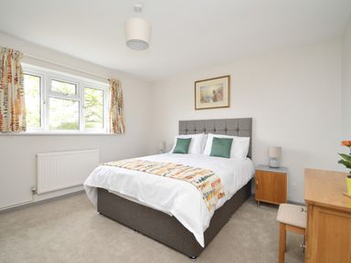 A bedroom with a bed a bedside table a lamp a window and a wooden dresser at Berwyn View Trelydan near Welshpool