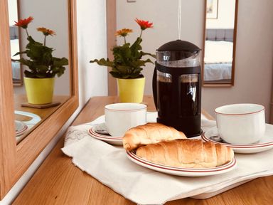 A wooden table with two croissants on a plate two cups a French press coffee maker and a potted plant at Berwyn View in Trelydan near Welshpool