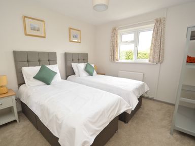A bedroom with two single beds each with white bedding and green pillows at Berwyn View in Trelydan near Welshpool