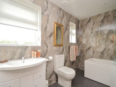 A bathroom with a sink vanity toilet bathtub and two windows at Berwyn View in Trelydan near Welshpool