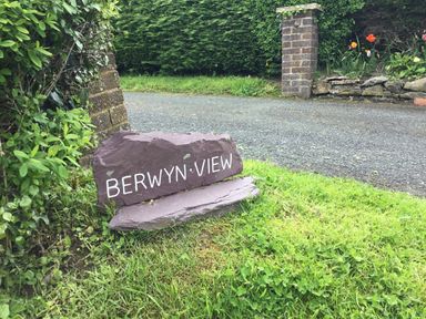 A stone sign reading Berwyn View on grass by a driveway with a brick pillar and hedges at Berwyn View in Trelydan near Welshpool