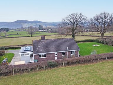 A brick house with a tiled roof and a skylight in a rural area with fields and trees at Berwyn View in Trelydan near Welshpool
