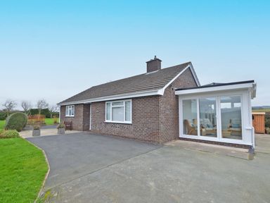 A single-story brick house with a tiled roof a paved driveway a glass extension and outdoor seating at Berwyn View in Trelydan near Welshpool