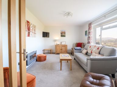 A living room with a gray sofa a wooden coffee table and armchairs at Berwyn View Trelydan near Welshpool
