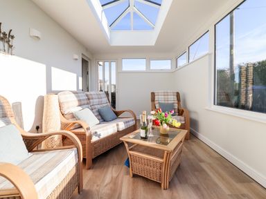 A sunroom with wicker furniture a glass coffee table and a skylight at Berwyn View in Trelydan near Welshpool
