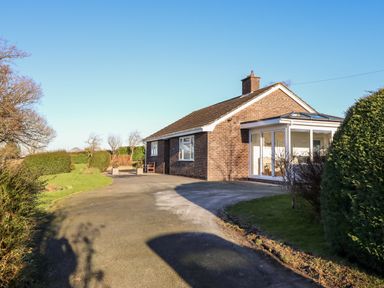 A brick house with a driveway surrounded by grass and hedges at Berwyn View in Trelydan near Welshpool