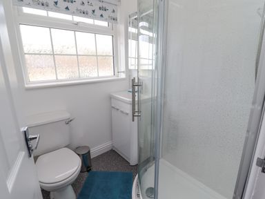 A bathroom with a toilet sink cabinet and corner shower at Beach Cottage in Portreath