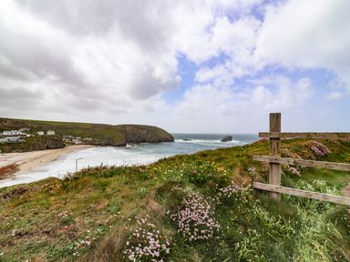 A coastal landscape with a sandy beach houses on cliffs and wildflowers on a grassy hill at Beach Cottage in Portreath
