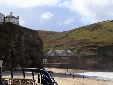 A beach with people walking near the water and houses on cliffs at Beach Cottage in Portreath