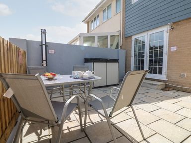 An outdoor patio with a table and four chairs next to a building at Beach Cottage in Portreath