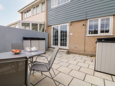 A patio with table and chairs and a fruit bowl next to a house with double doors at Beach Cottage in Portreath