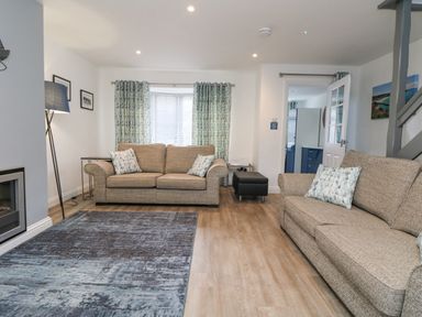 A living room with two sofas pillows curtains a floor lamp and a rug at Beach Cottage in Portreath