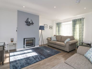 A living room with two sofas a fireplace and patterned curtains at Beach Cottage in Portreath