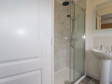 A bathroom with a glass shower enclosure and a pedestal sink at Laurel Lodge Bossiney Bay Holiday Park near Tintagel