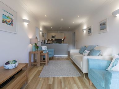 A living room with a sofa armchair rug and kitchen area at Atlantis in St Ives