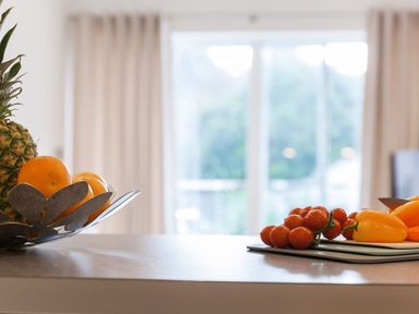 A kitchen counter with a fruit bowl containing pineapple and oranges and a cutting board with cherry tomatoes and yellow bell peppers at Atlantis in St Ives